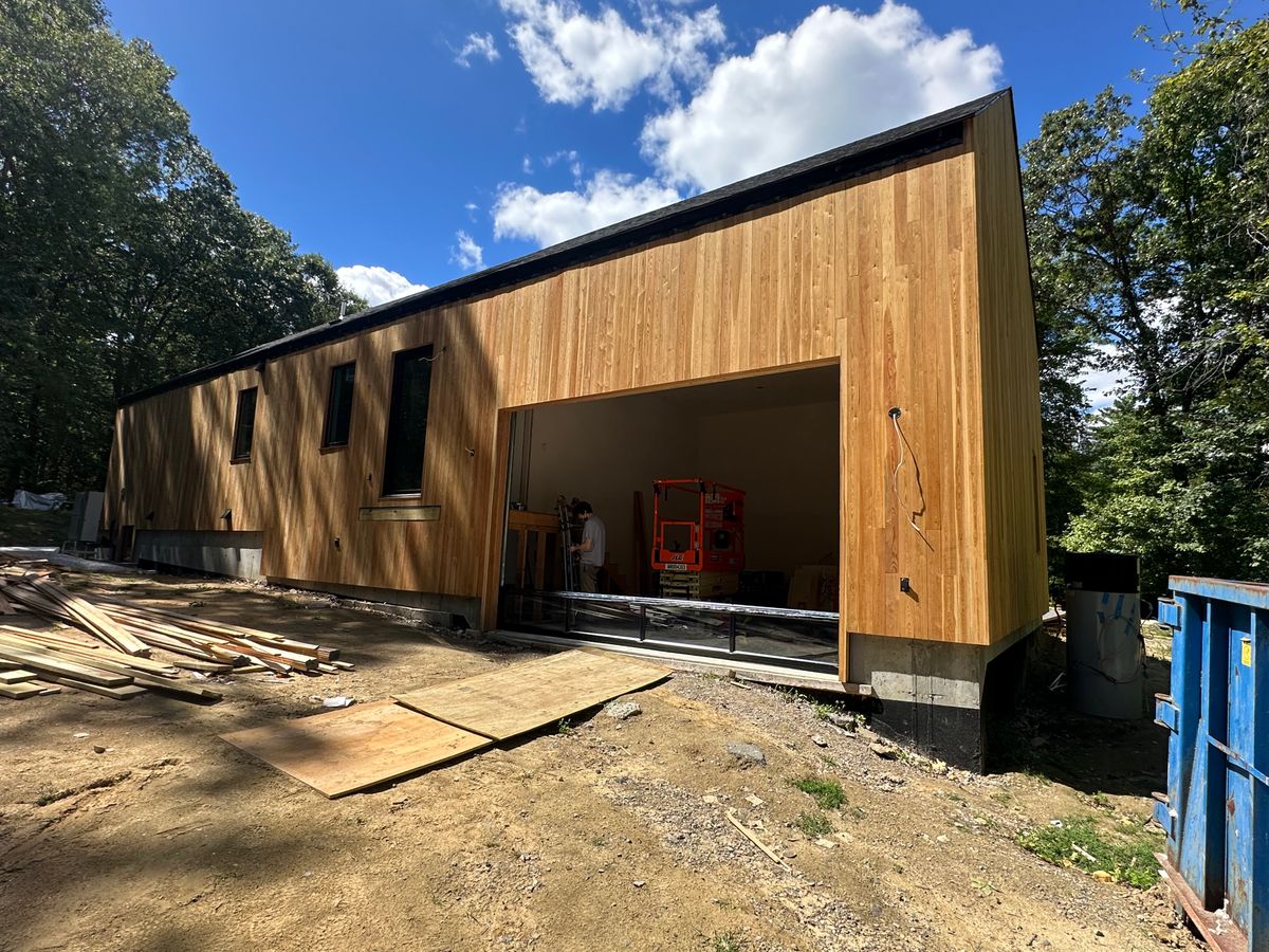 Modern cedar building with large garage opening under construction